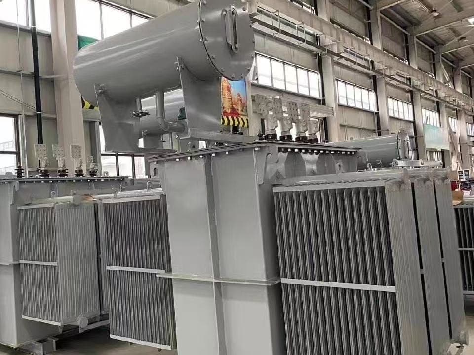Several large oil-immersed transformers standing in a factory hall