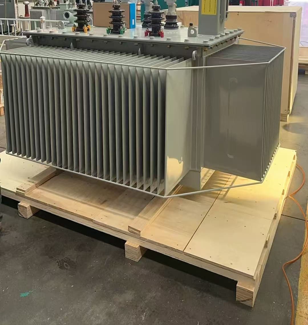 Oil-immersed transformer on a timber skid beside a plywood crate