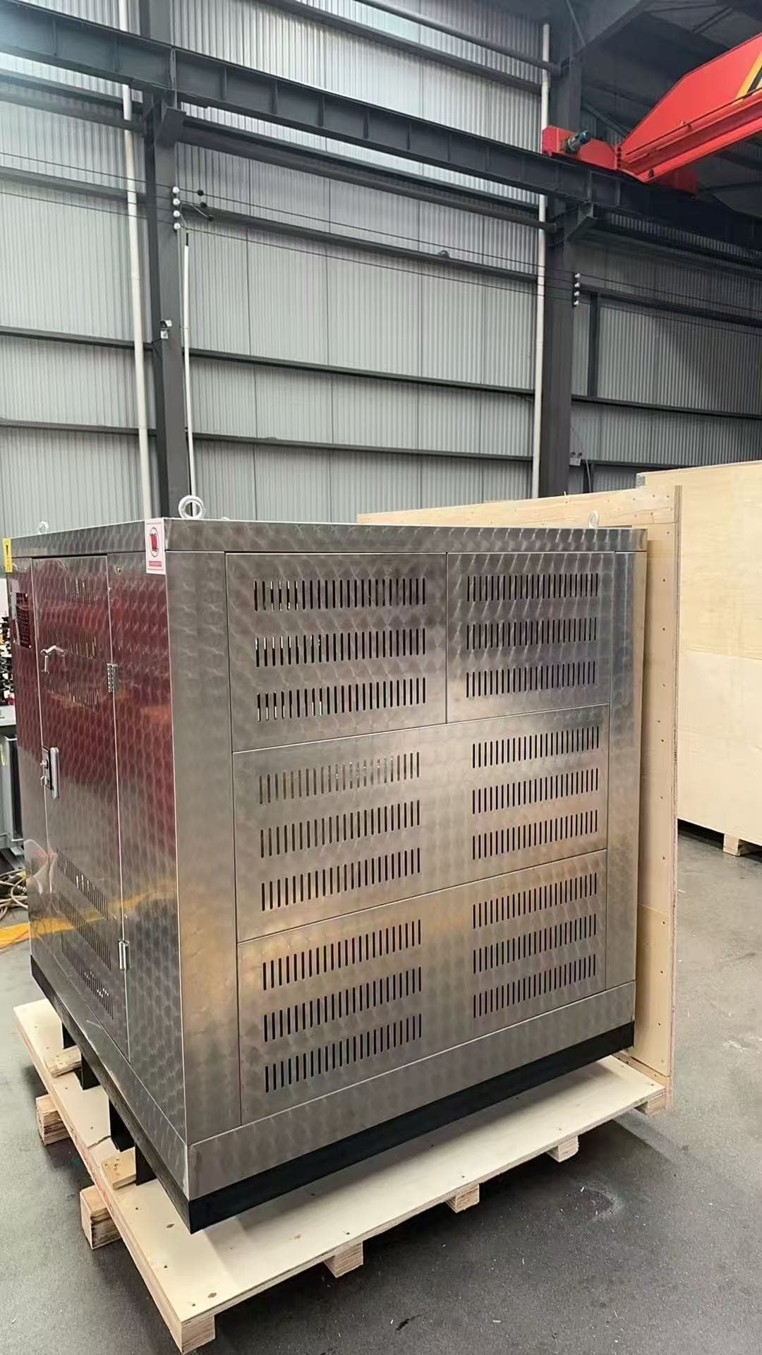 A stainless steel ventilated enclosure being crated in plywood on the factory floor