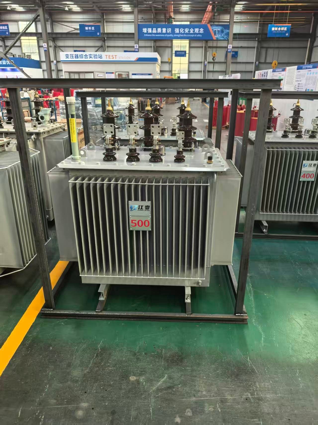 An oil-immersed transformer with the company plate, in front of the test station building in the factory hall