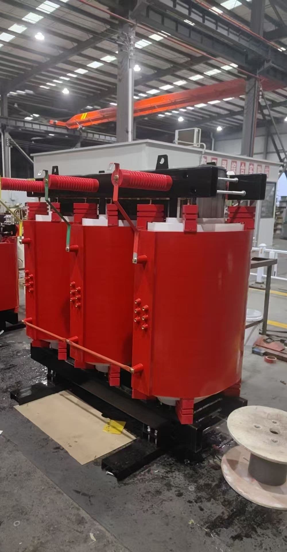 Cast resin dry-type transformer with red coils on the factory floor