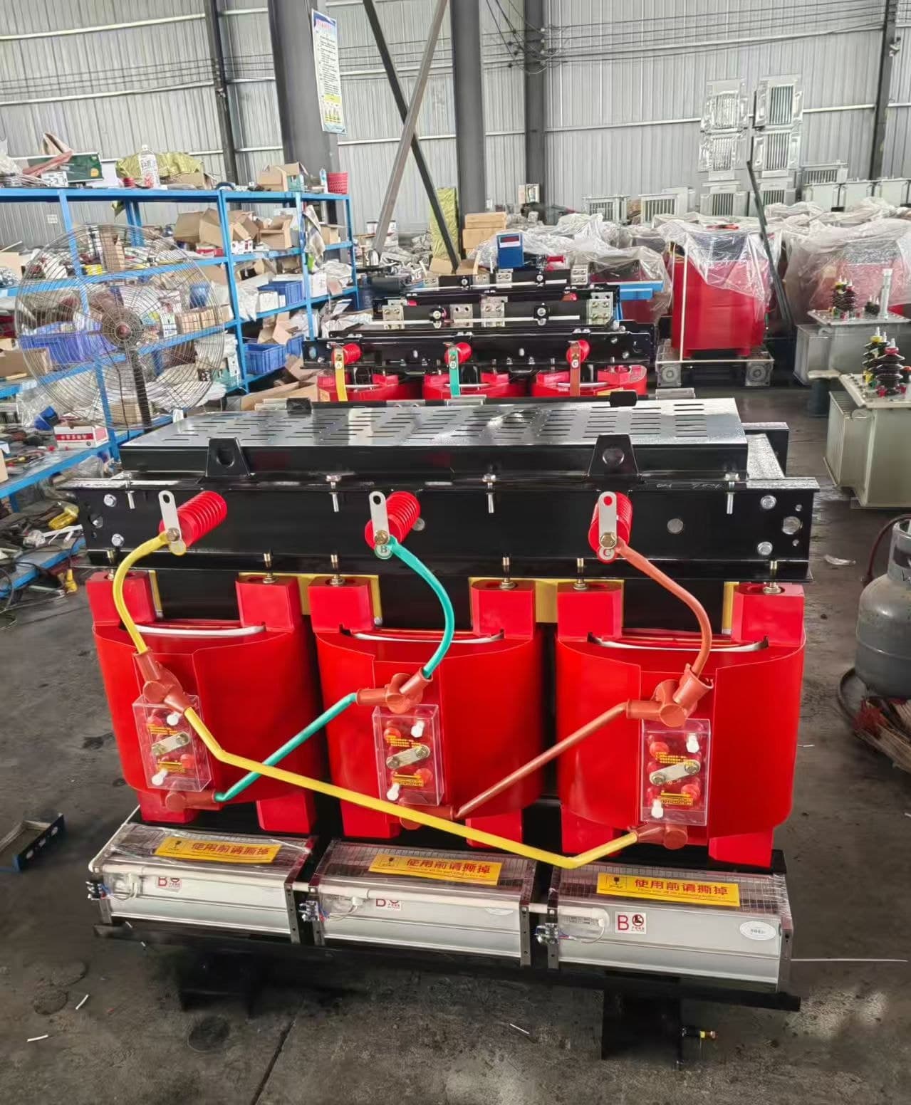 Cast resin transformer with red coils and connected leads, a row of units behind it