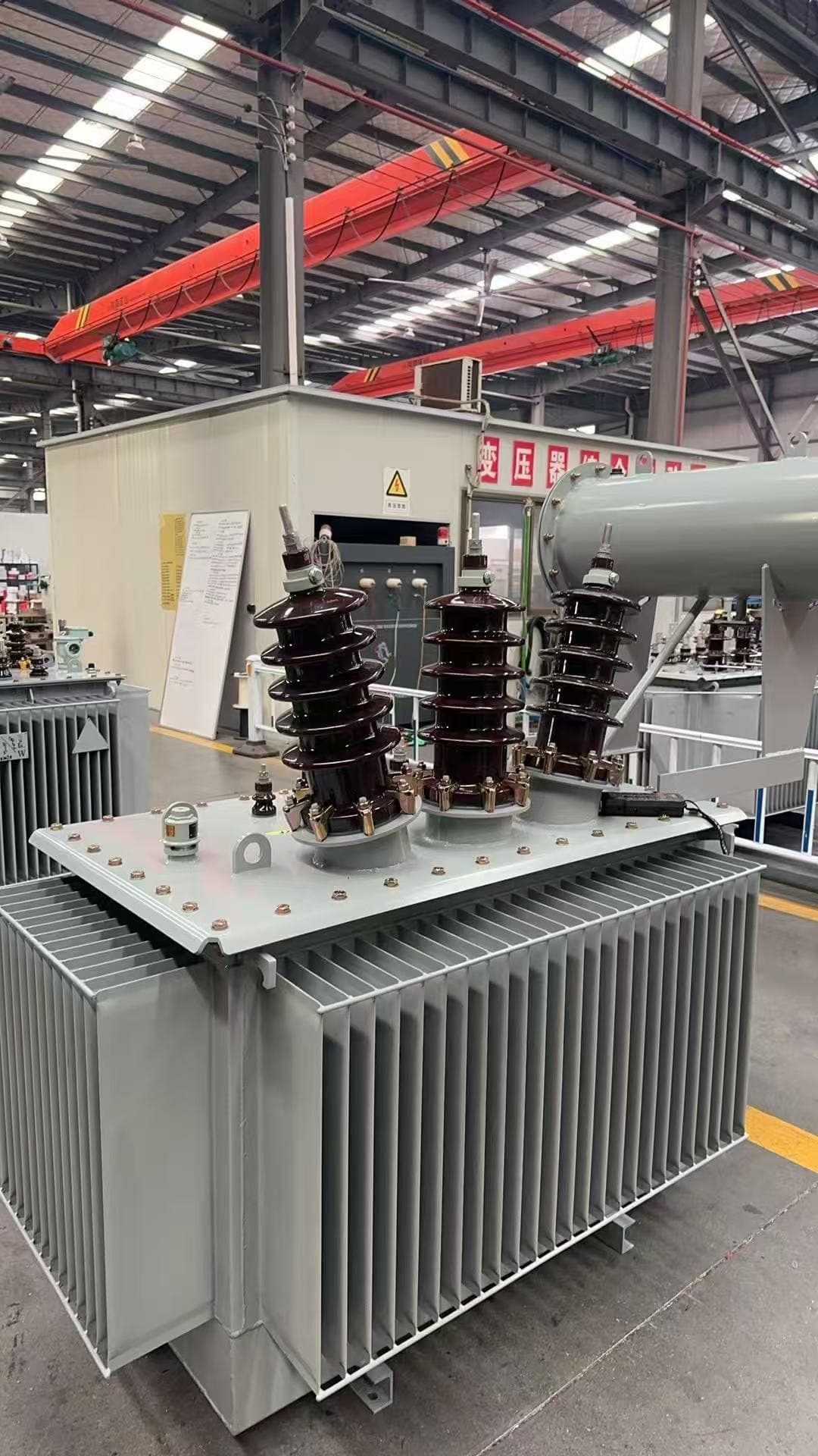 Oil-immersed transformer with a conservator, in front of a building in the factory hall